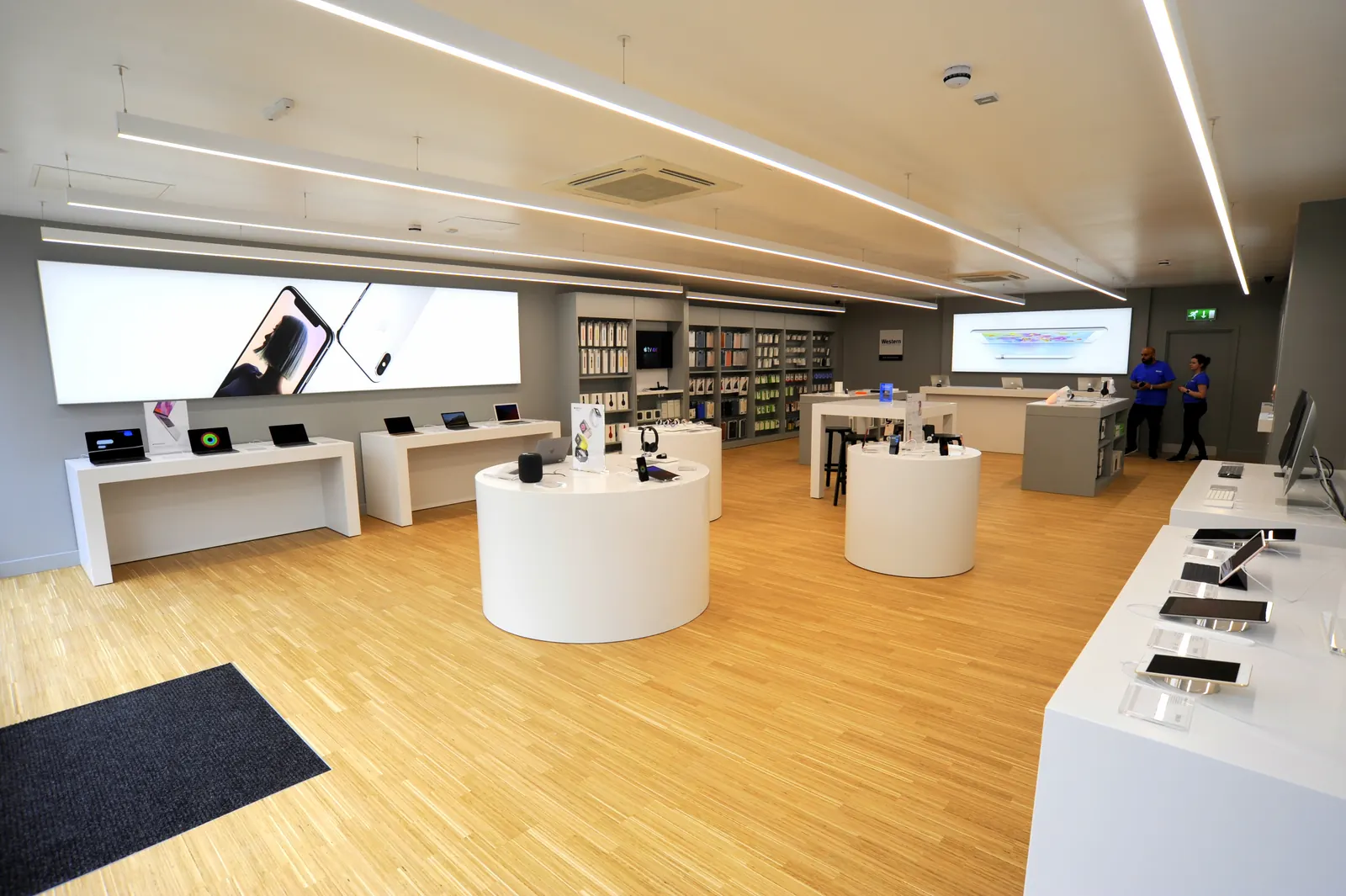 A finished technology store with white display plinths, laptop benches and an oak floor