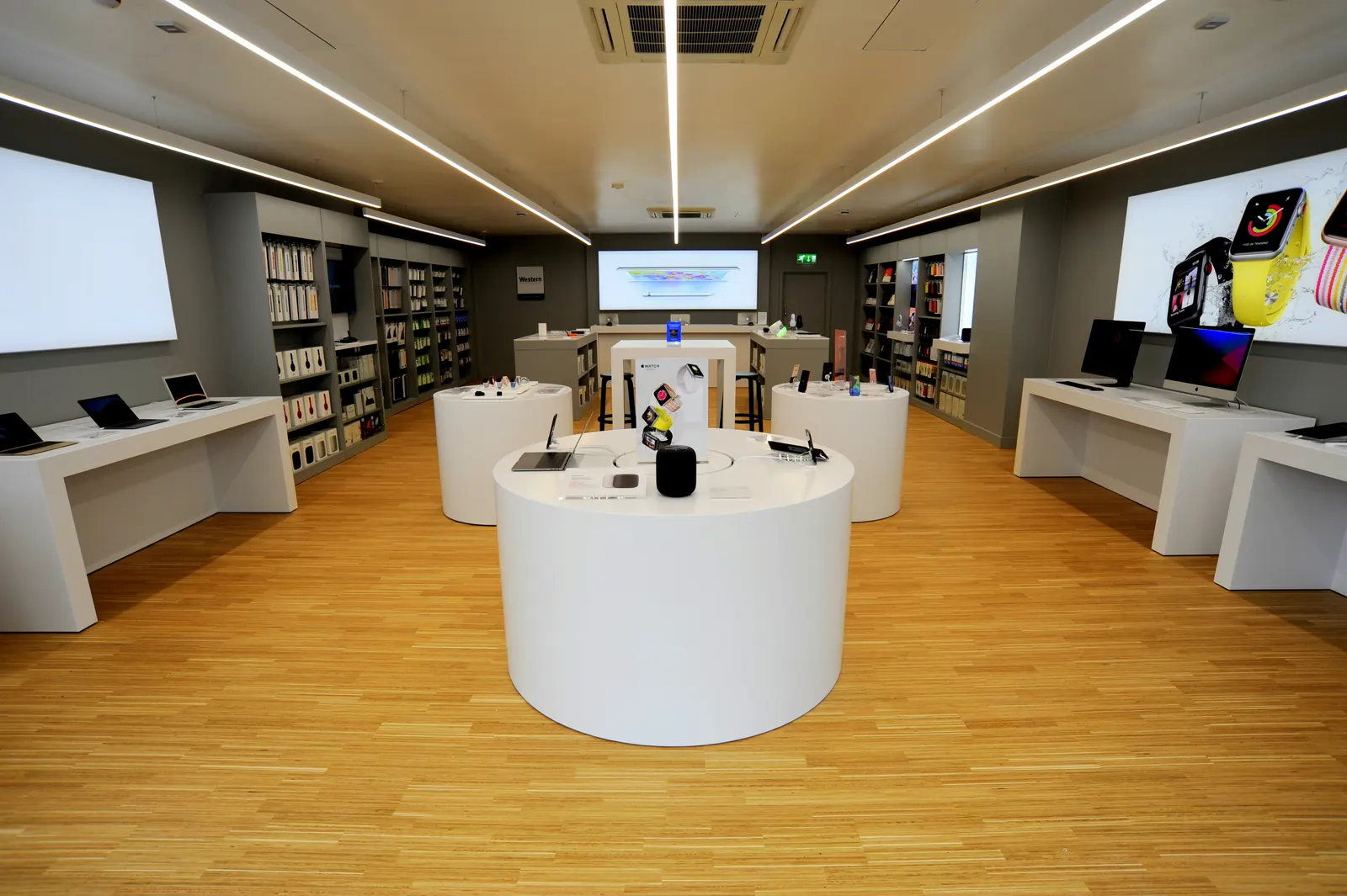 A finished Apple Premium Reseller store with white display plinths, laptop benches and an oak floor