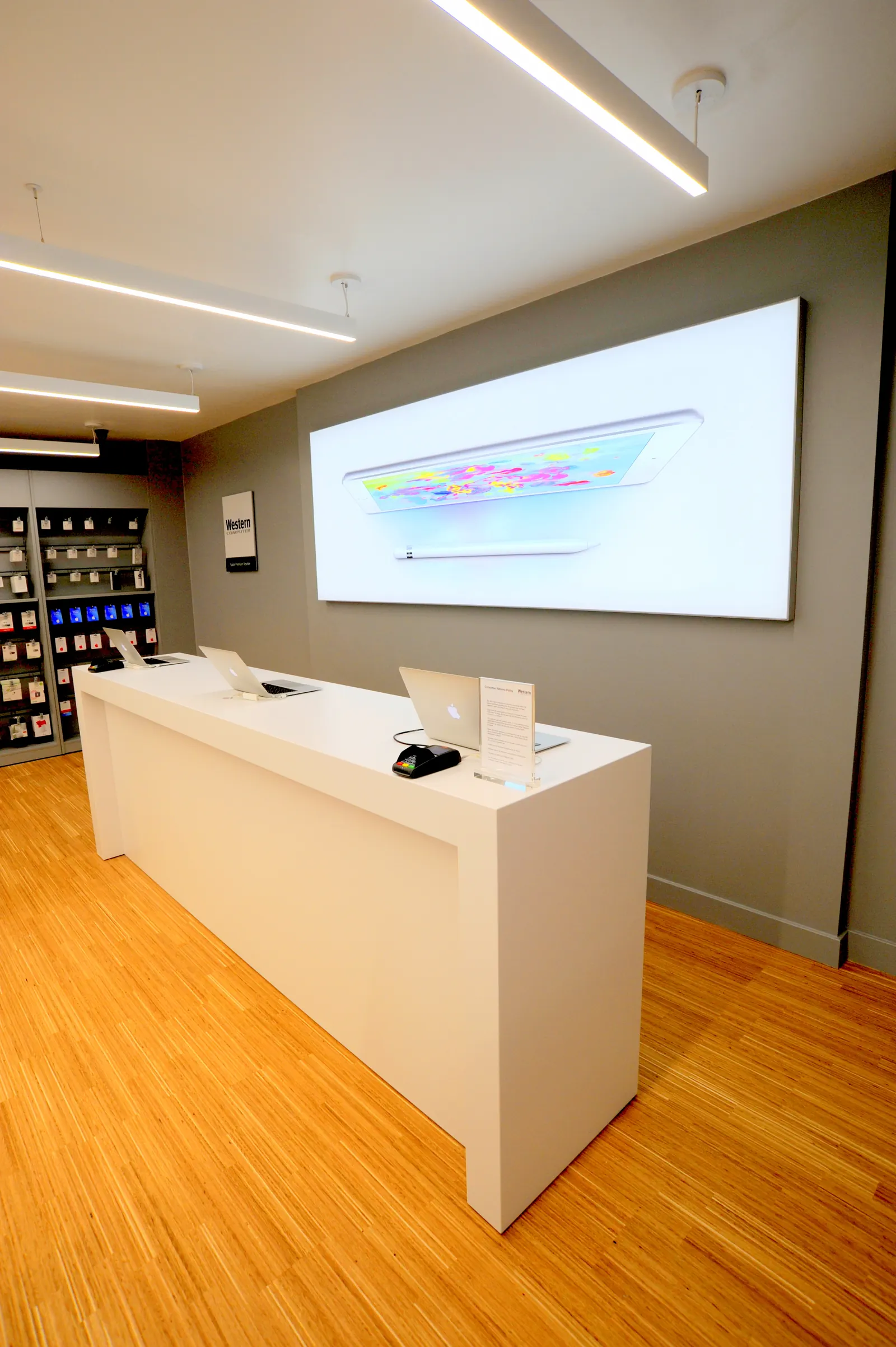 A white service counter in front of a backlit wall graphic