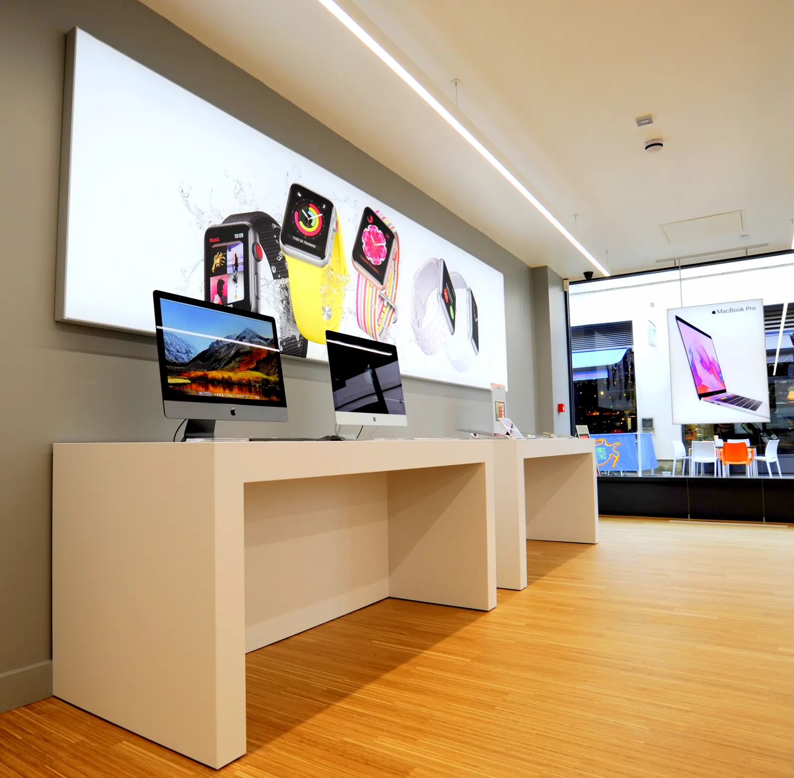 Laptop benches beneath a backlit wall graphic