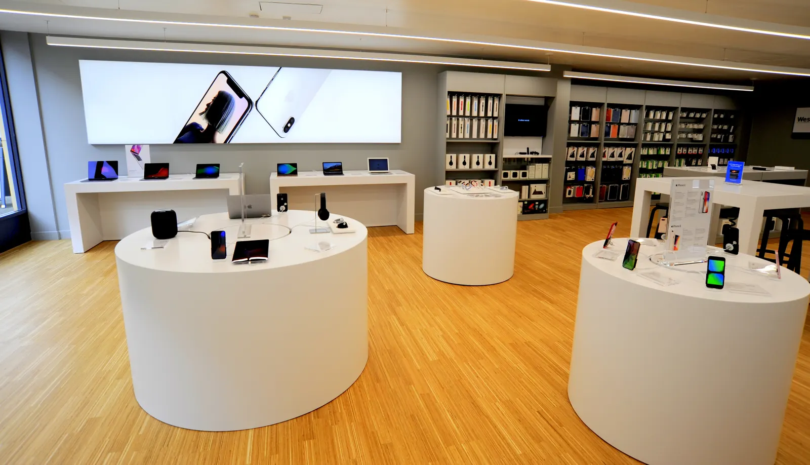Round white display plinths and a full-width lightbox in a finished technology store